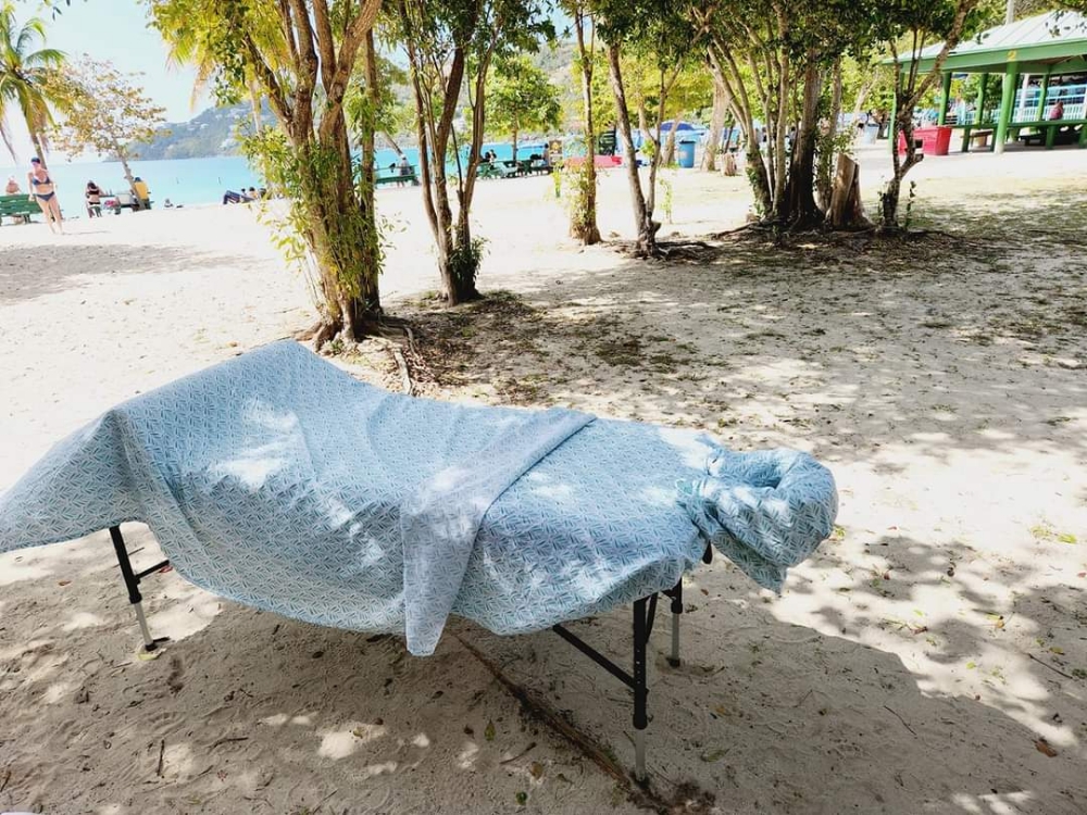 Massage table set on the beach under shade trees