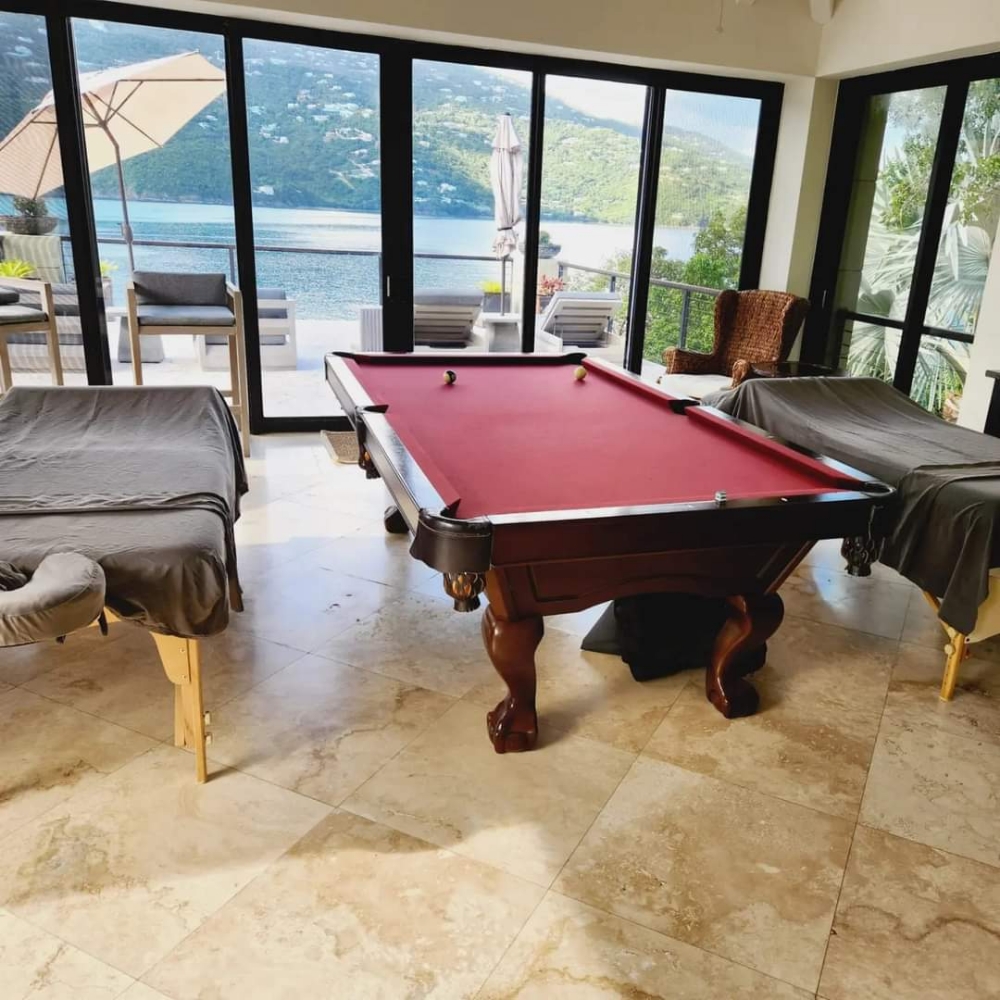 Couples massage tables flanking a pool table room with bay view