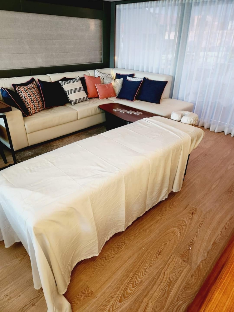 Indoor massage setup with cream sectional and designer pillows